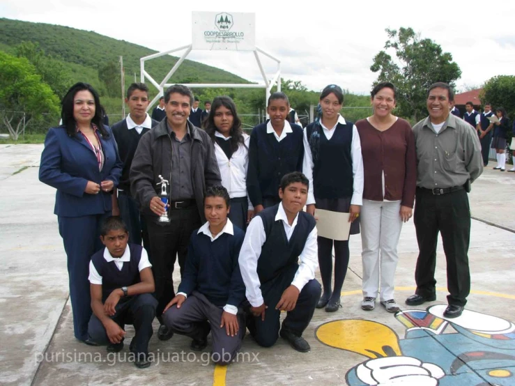 a group of children and their coach pose in front of a basketball hoop