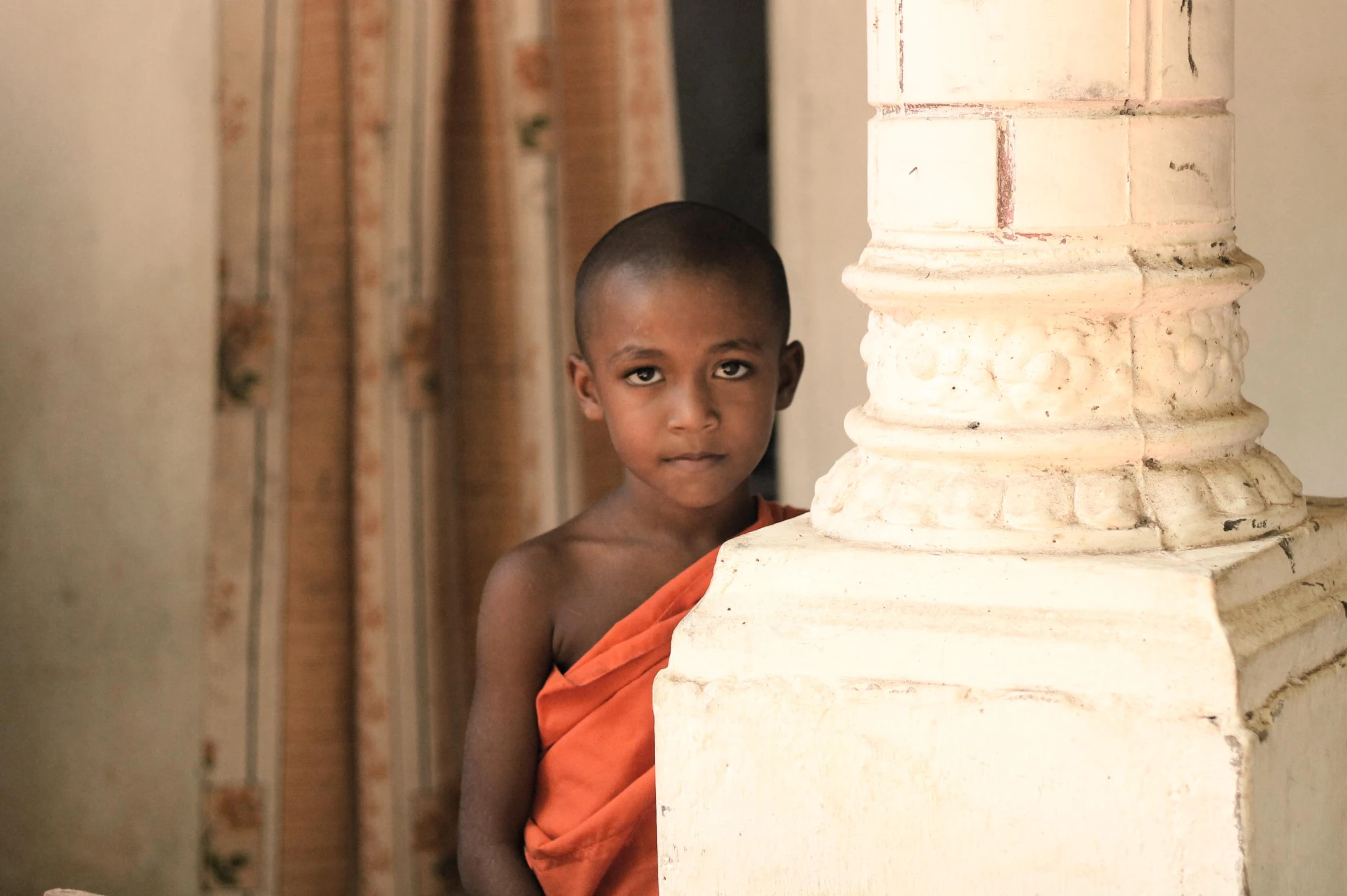 a small boy that is standing by a pillar