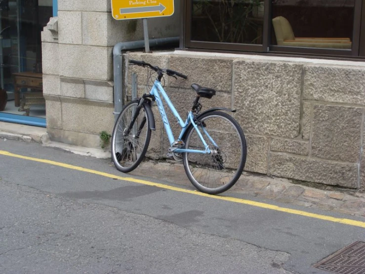 a bicycle is sitting near a sign on a sidewalk