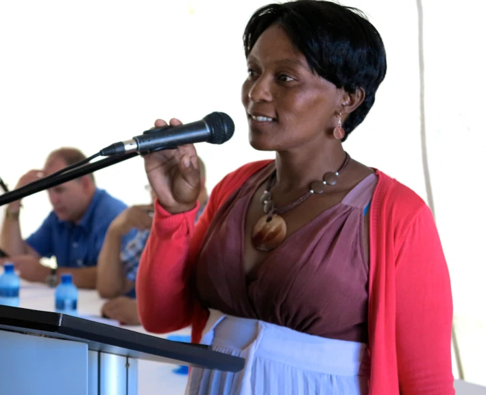 a woman talking into a microphone in front of a crowd