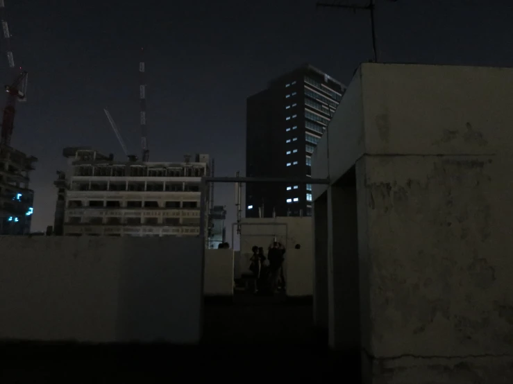 a couple of people stand on a roof at night