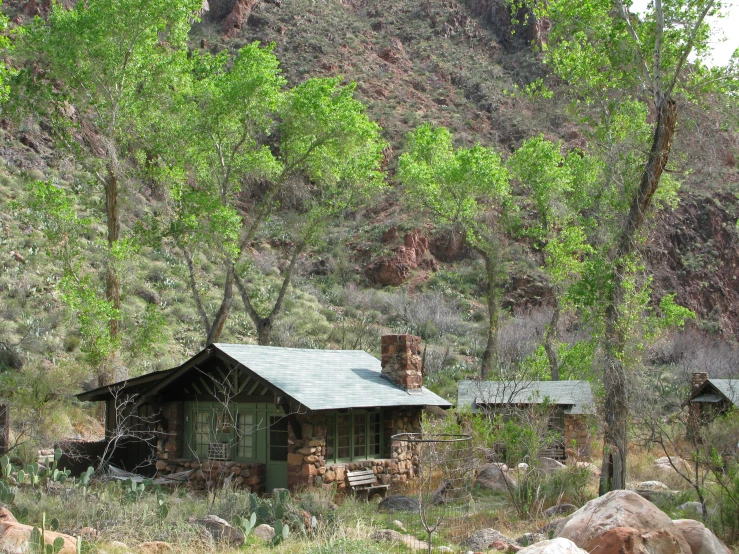 an old cabin sits among some trees and rocks