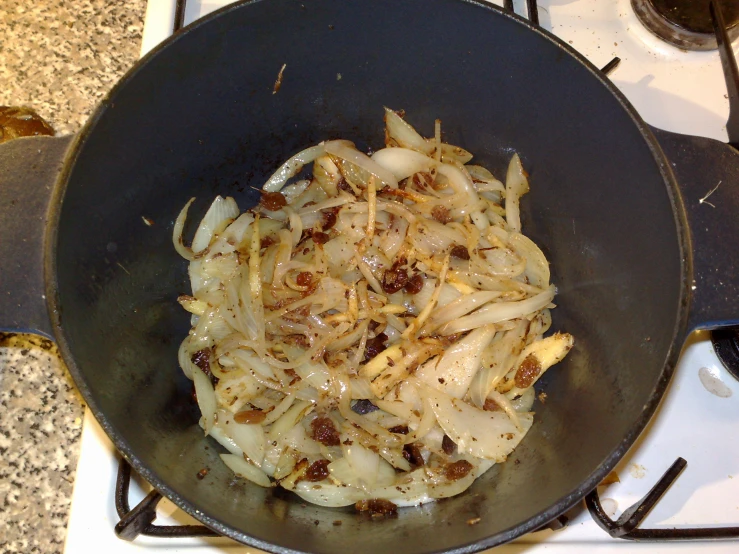 a wok with onions on a stove top