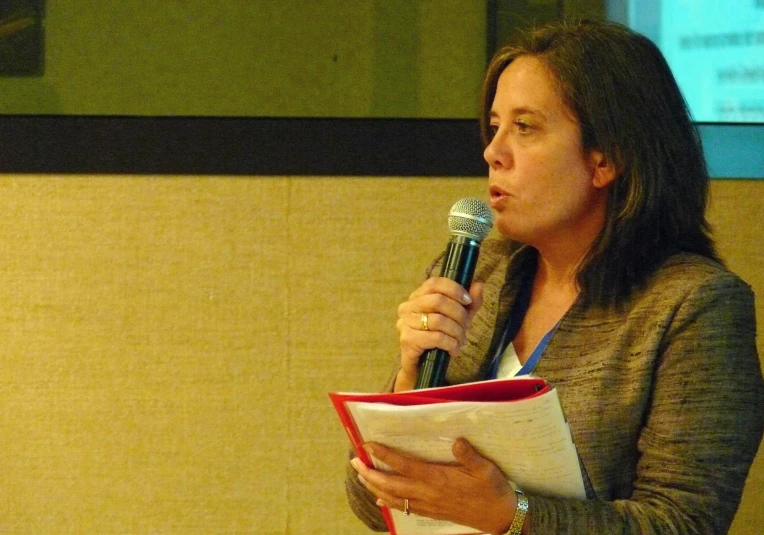 a woman in business suit talking into a microphone