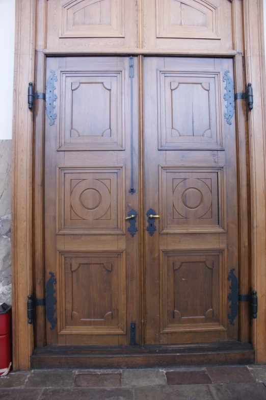 two wood doors with metal handles on a stone wall