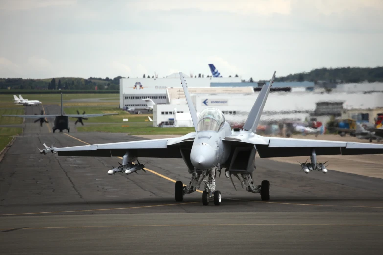 a military airplane on the runway next to some other planes