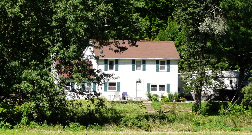 a white house with trees surrounding it and some grass