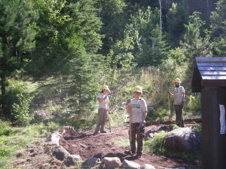 the men are hiking through the forest on the dirt road