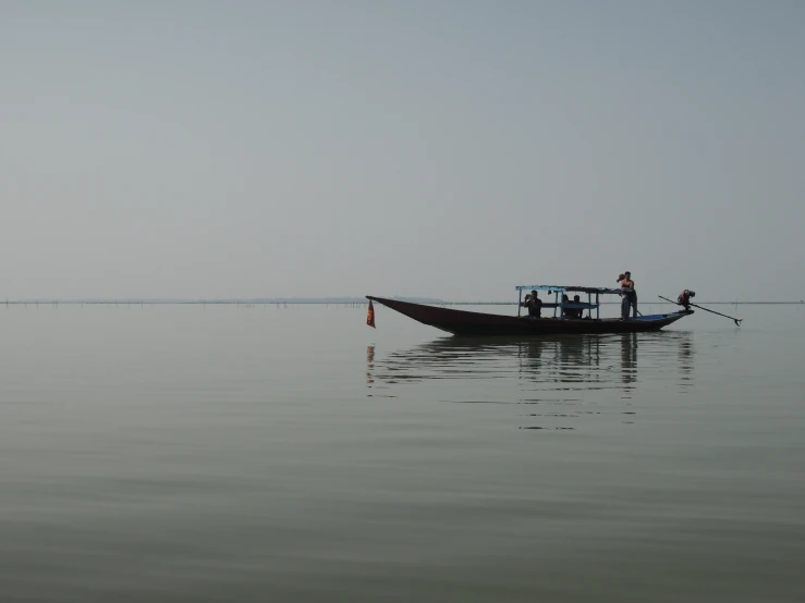 two men are sitting in a boat on a calm lake