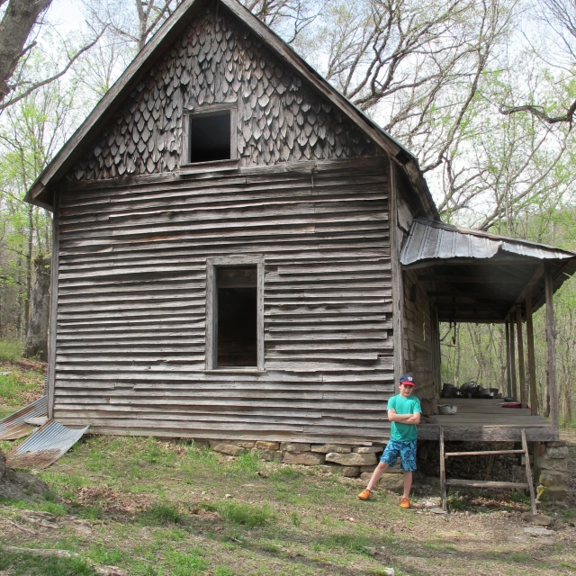 a child stands outside a small wooden building