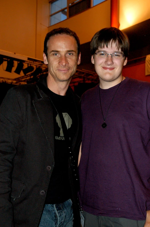 a man with glasses is standing next to a smiling young man