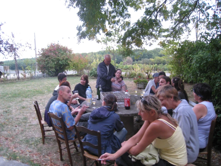 a family gathered around a table having a meal outdoors