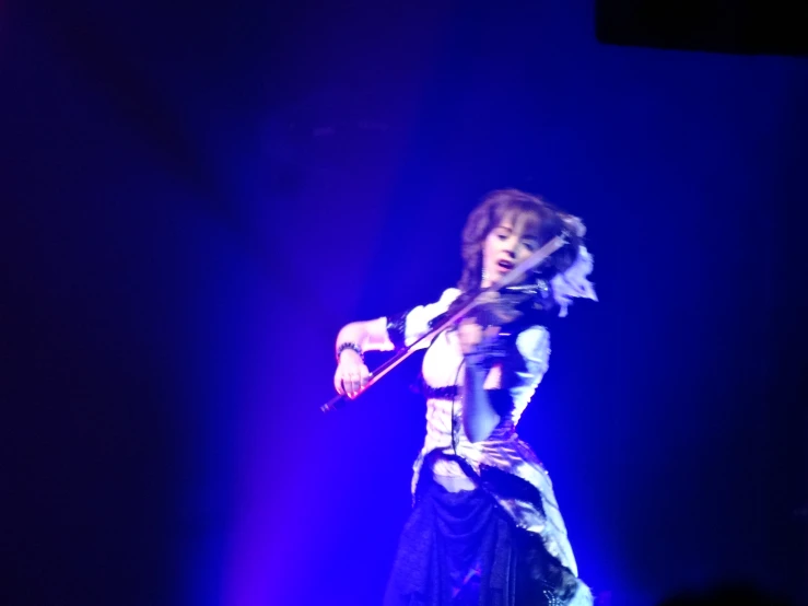 a woman is playing the violin on stage