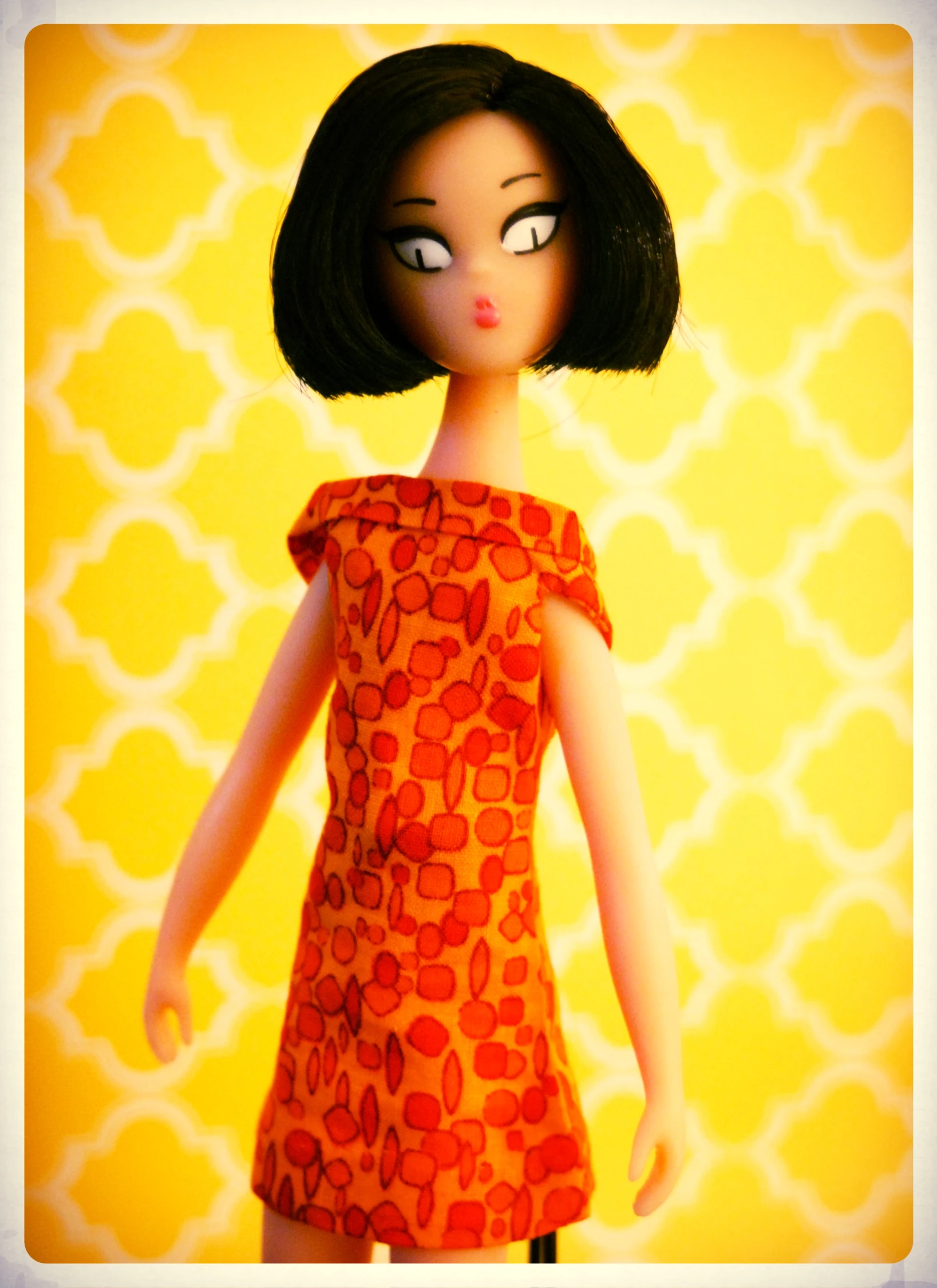 a doll is posing on a yellow background