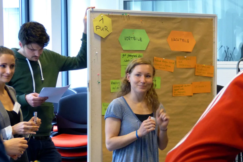 several people standing in an office area next to bulletin board