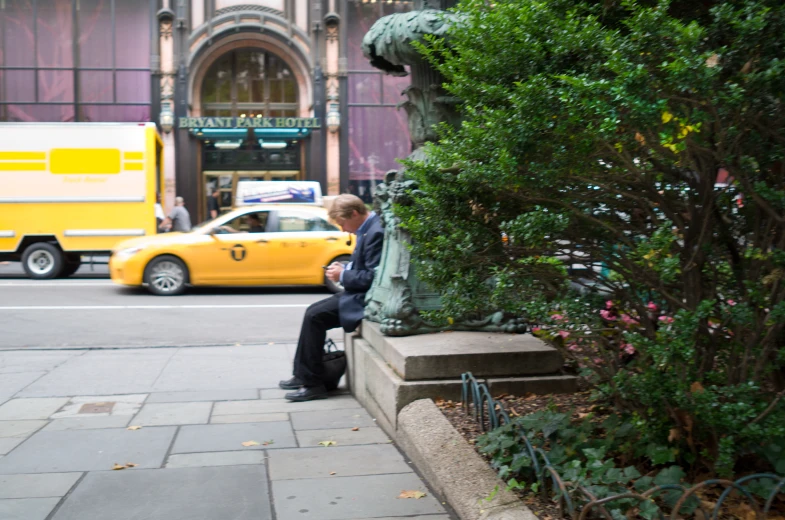 a man sitting on top of a stone bench next to a tree