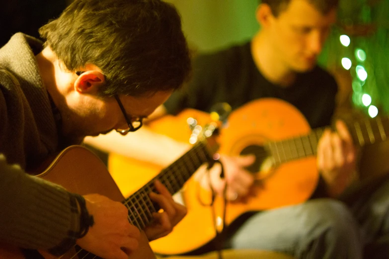 two men sit together and play a song while another man is sitting down