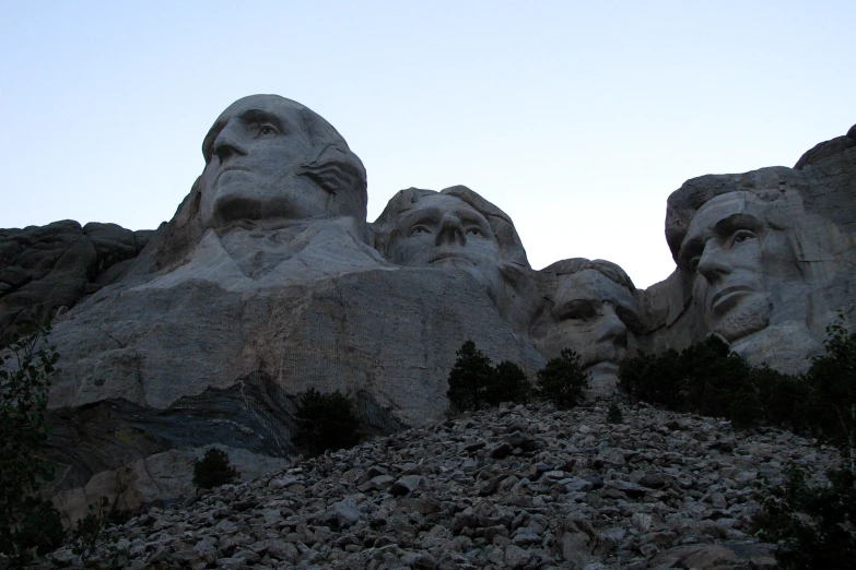 a group of heads are in the middle of several large statues