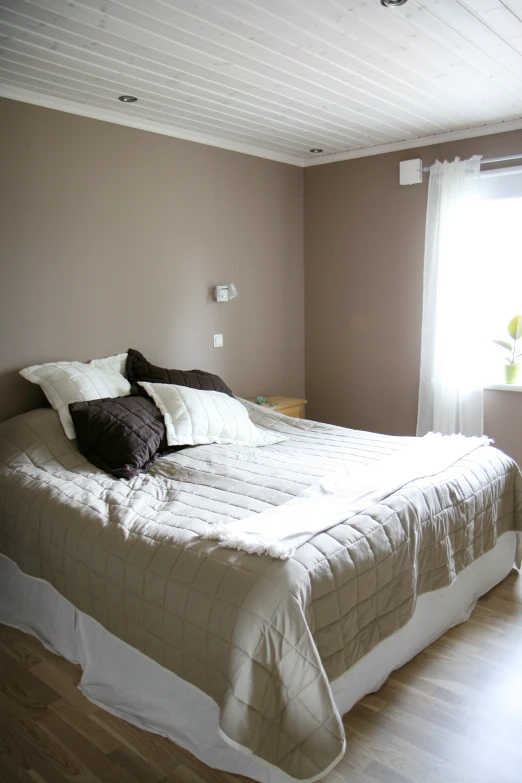 a bed room with a neatly made bed and white curtains