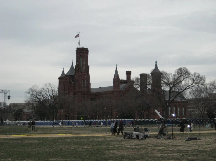 many people are on the grass by some big buildings