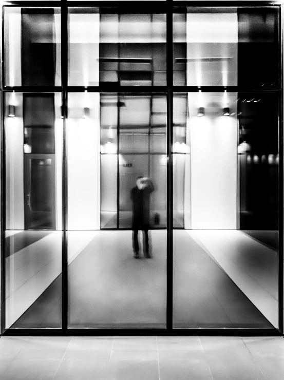 a man in black jacket standing behind glass door