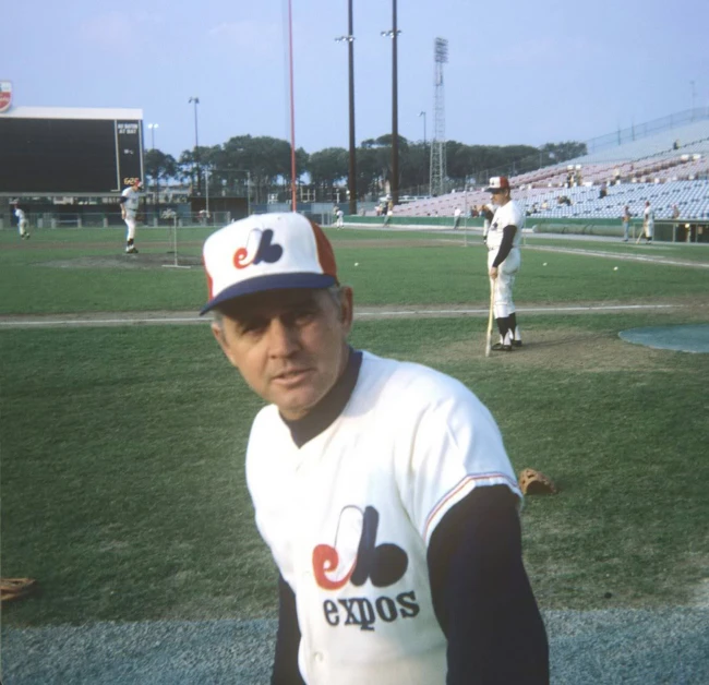 a man in white and black baseball uniform standing on field with ball glove