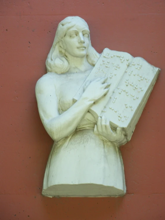 a white statue is holding a book and wearing a headband