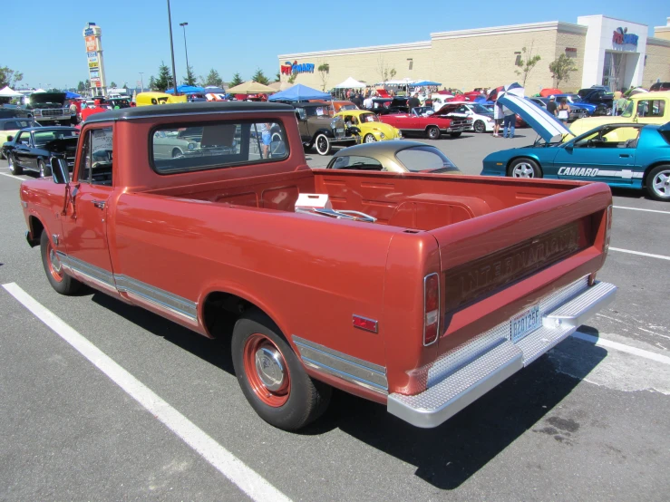 an old orange pickup truck is parked next to a pile of antique cars