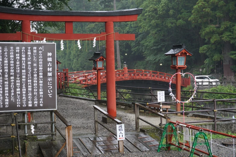 a red wooden bridge on a lake surrounded by green forest