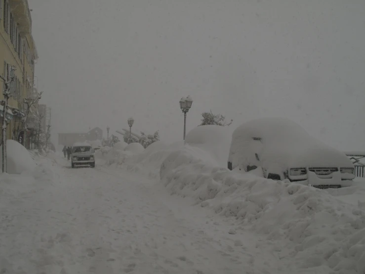 the streets are covered in heavy snow as cars and trucks are parked on the side of the road