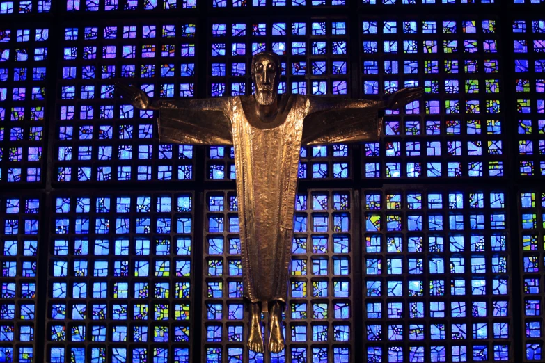 a sculpture of a crucifix in front of stained glass