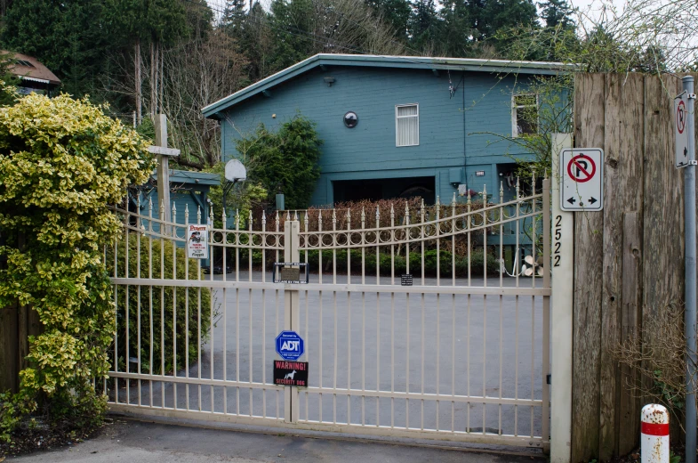 a gated entrance at a blue house, with no parking in front