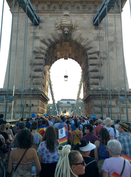 a large group of people stand underneath an arch in a city