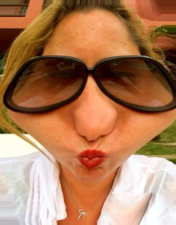 a woman in large oval glasses making a silly face