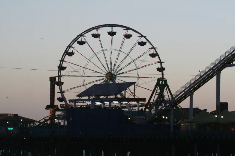 the ferris wheel is moving slowly along the side of the pier