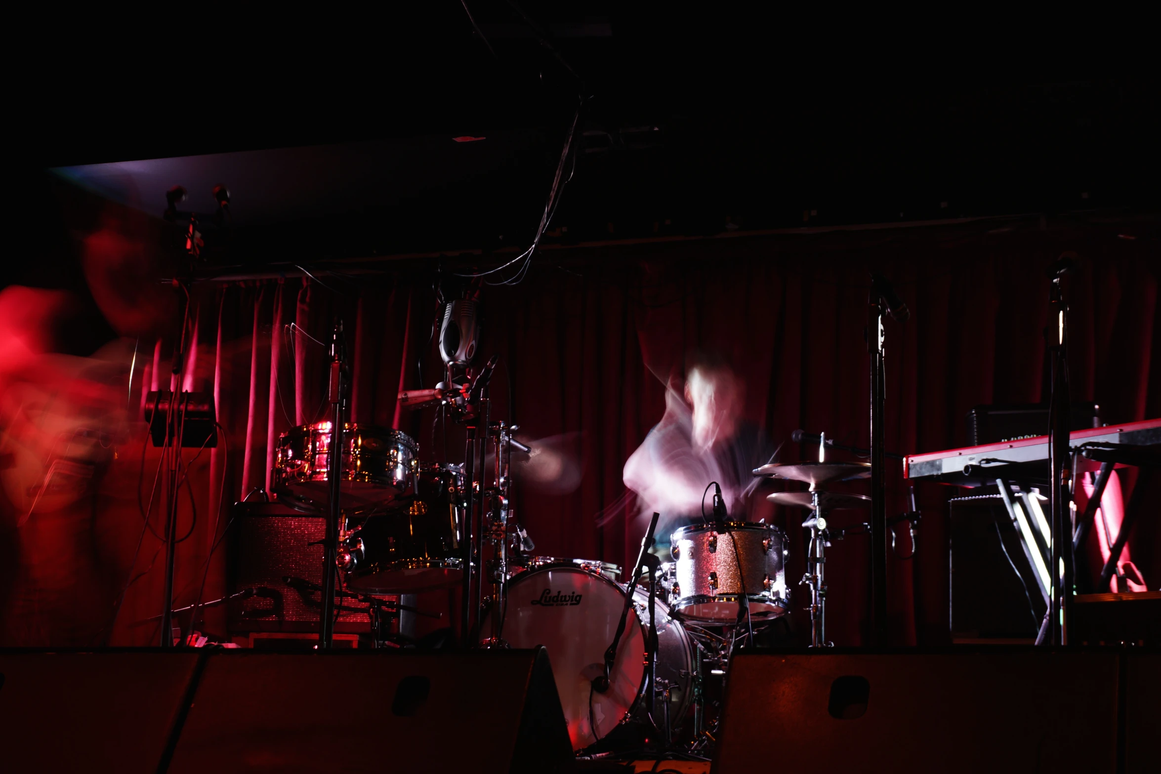 a person playing instruments while people watch from behind a stage