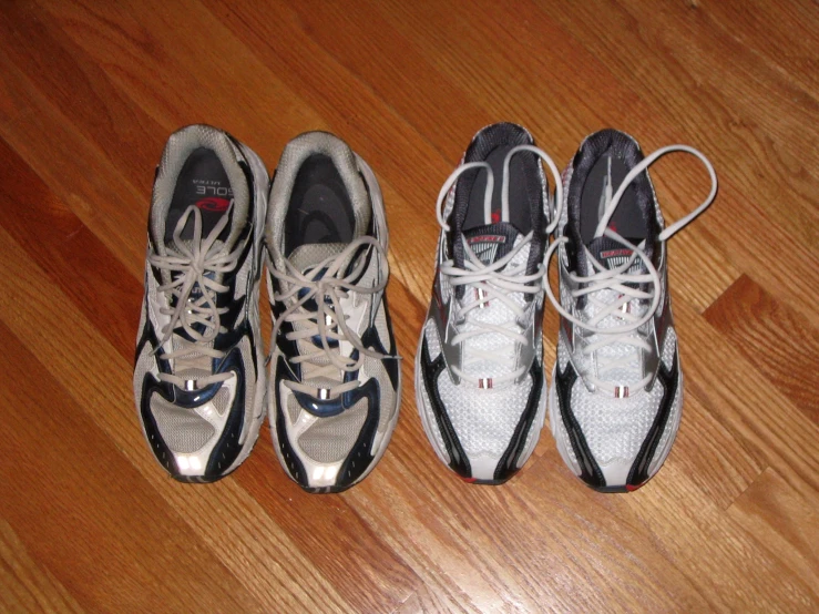 three pairs of sneakers on a hardwood floor