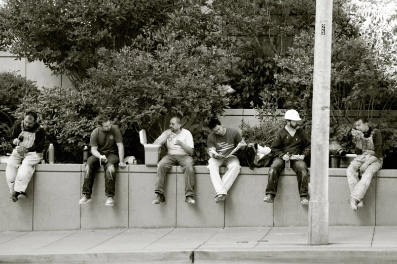 a group of men sitting on a wall talking