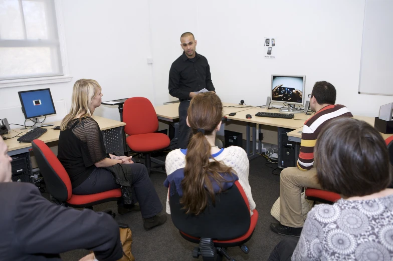 there is a man standing in front of a group of people on chairs