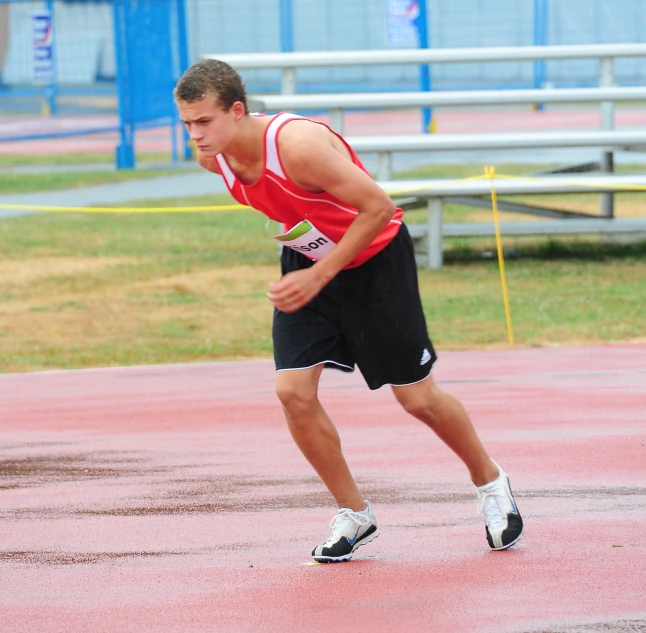 a male athlete in red shirt and black shorts playing with a ball