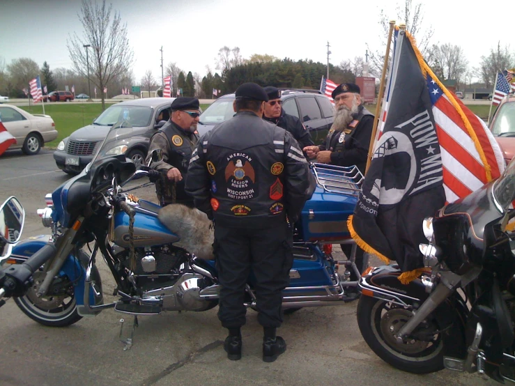 several motorcycle riders standing around one another talking