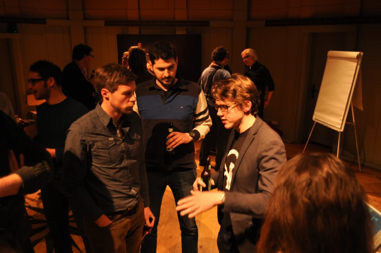 three men with glasses are talking together in front of a microphone