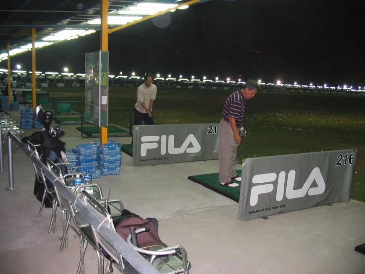 a couple of men playing a game of golf at night