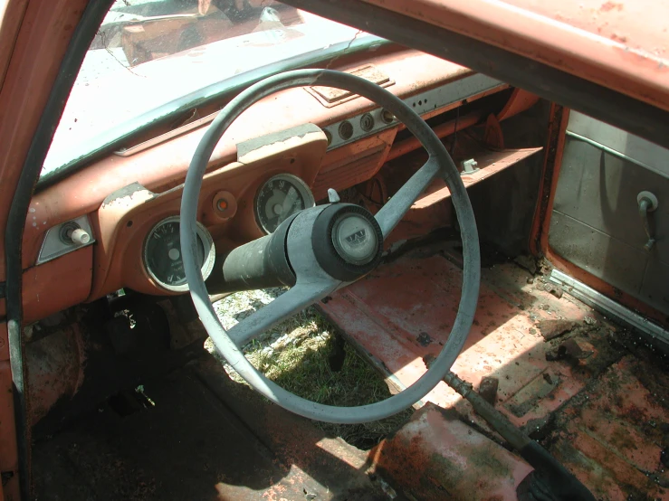 an old dirty car with a steering wheel on the dash line