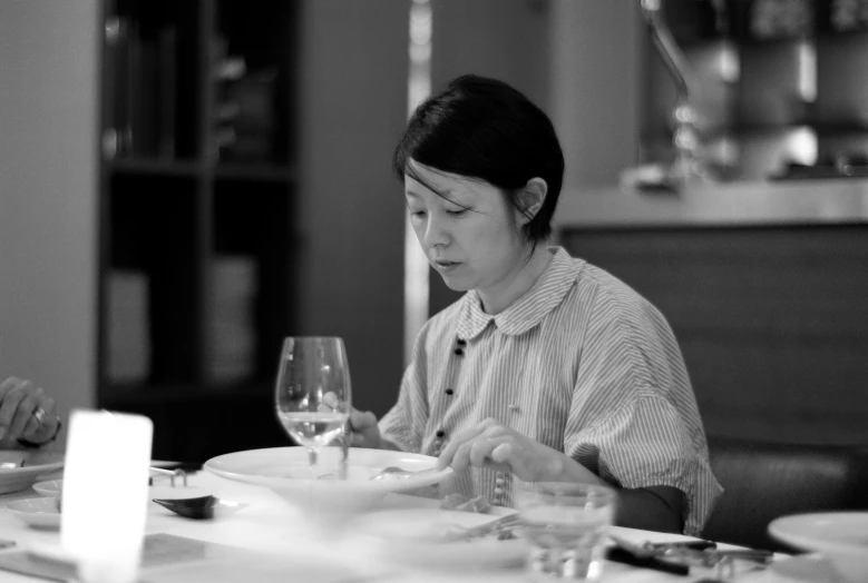 a black and white po of a woman eating at a table