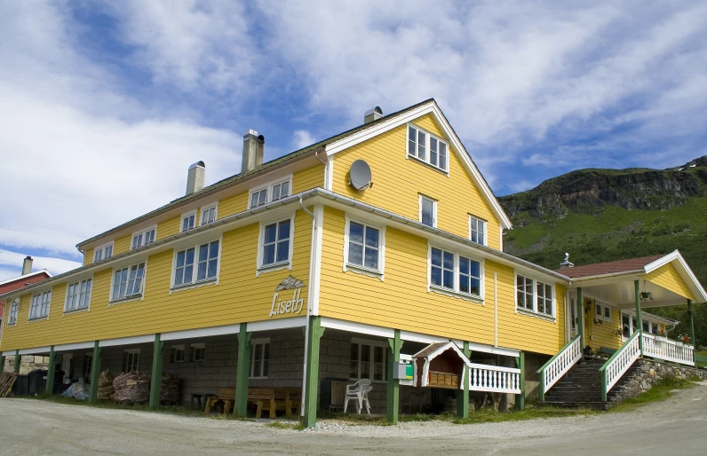 a tall yellow house with a big slope in the background