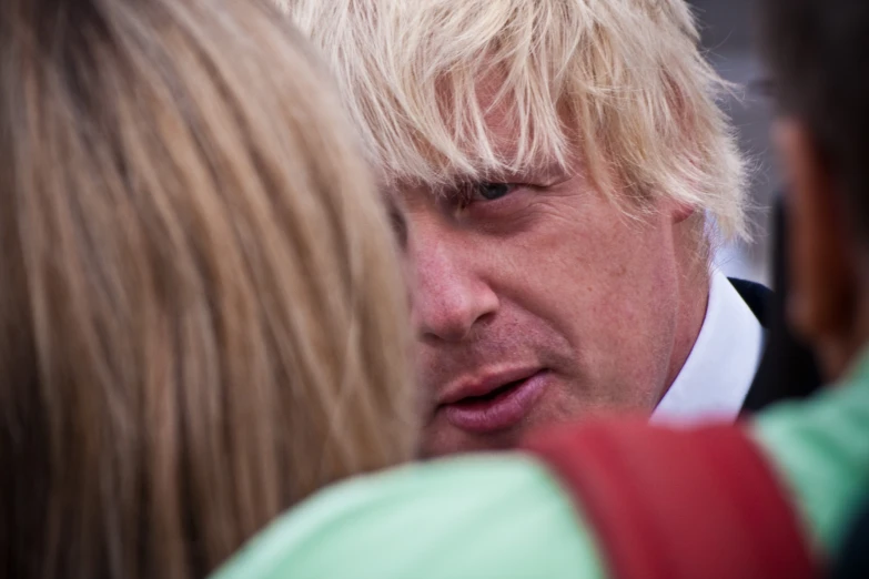 man in white and blonde wig staring at his phone