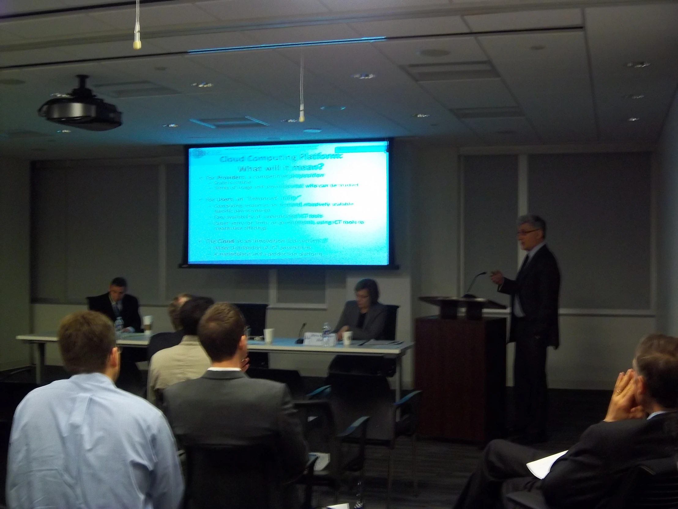 a group of people are gathered around tables in a room while one person is giving a presentation