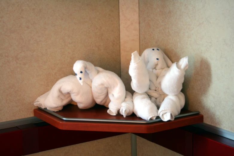 white stuffed animals arranged on a wooden shelf