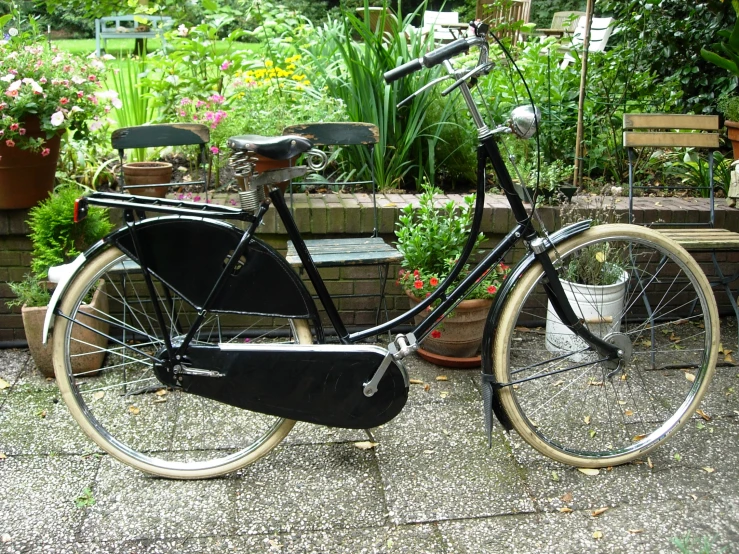 an old fashioned bicycle with a basket and seat sits outside in a garden